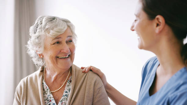 You care, that's what matters Shot of a happy senior woman being cared for by a young nurse in a retirement home hand on shoulder photos stock pictures, royalty-free photos & images