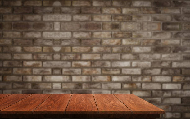 istock Wood table in front of brick wall blur background. 1165980636