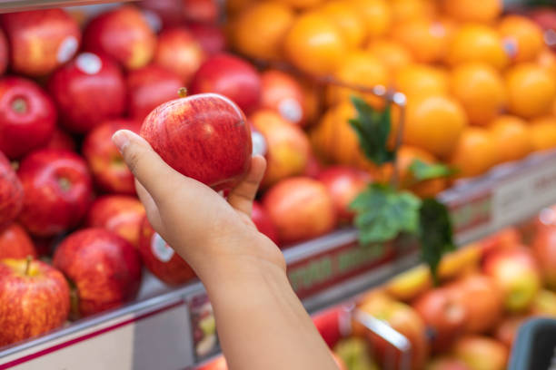Human hand picking apple at fruit store stock photo