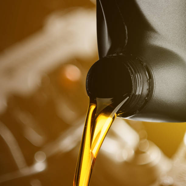 istock Pouring oil lubricant motor car from black bottle on engine background object transportation design 1165990618