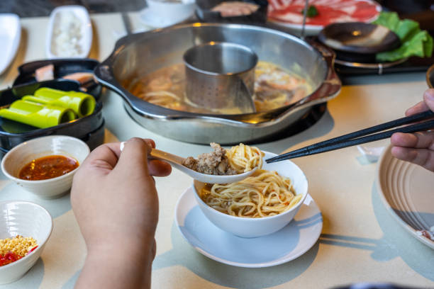 Rear view of woman hands eating hotpot