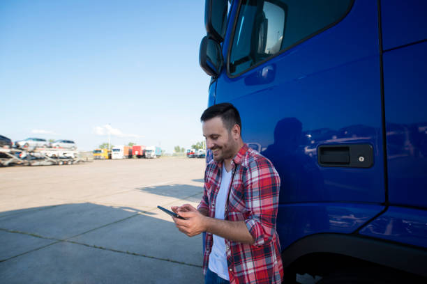 彼のトラック輸送車両の前にタブレットを持つトラック運転手。 - truck semi truck blue truck driver ストックフォトと画像