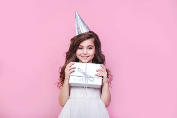 Photo of Portrait of cute little girl with gift box on pink background. Birthday party