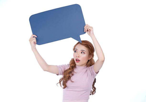 istock Young woman holding a speech bubble and smile on a gray background 1166001063