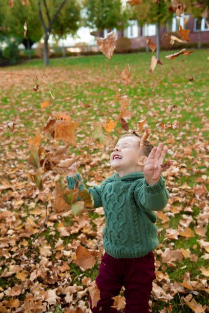 istock cute boy run among fallen leaves in autumn park. 1166006609