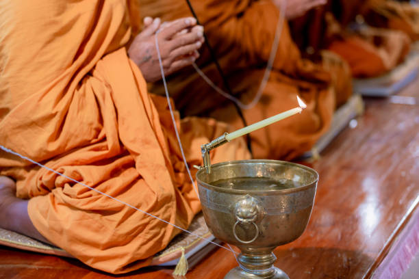 istock Buddha monk hold candlestick above holy water bowl. 1166007497