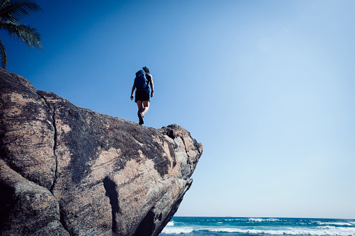 Woman hiker walking on seaside rock cliff edge