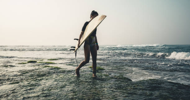 istock Woman surfer with surfboard going to surf 1166013615