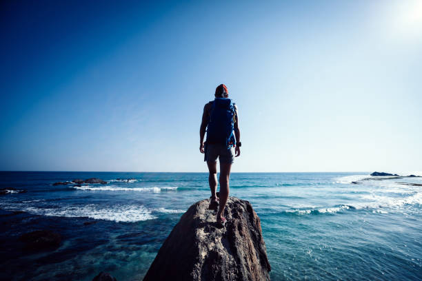 istock Woman hiker walking on seaside rock cliff edge 1166013645
