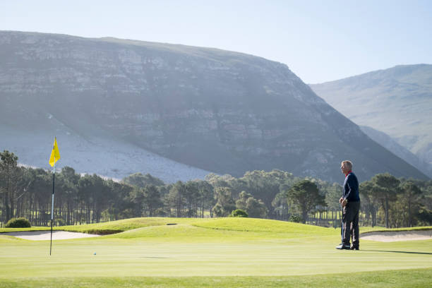istock Senior golfer putting on golf course by mountain 1166013759