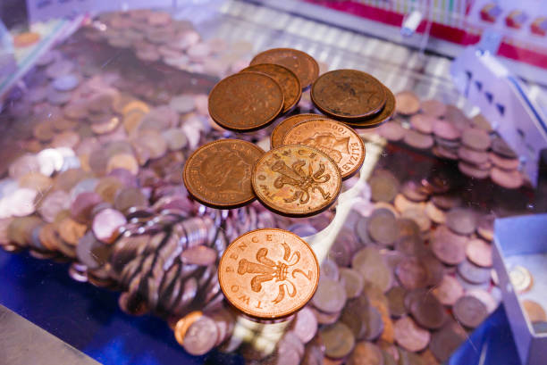 two-pence coins lie on the glass on top of a 2p nudger machine in a seaside amusement arcade. - british currency coin two pence coin british coin imagens e fotografias de stock