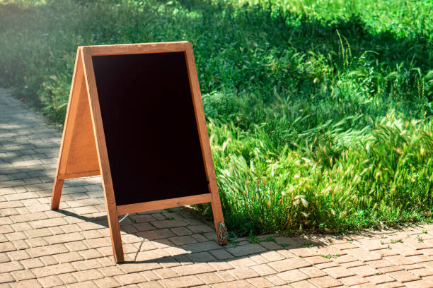 istock A black chalkboard stand on wood for a restaurant menu in the street. Empty menu board on street. Empty menu board on street on the pub or restaurant background. Beauty and minimalism style 1166016633