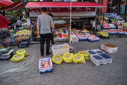 MISHAN, CHINA - JULY 27, 2019: Unidentified local people selling and buying products at street in Mishan. Mishan is a county-level city in the southeast of Heilongjiang.