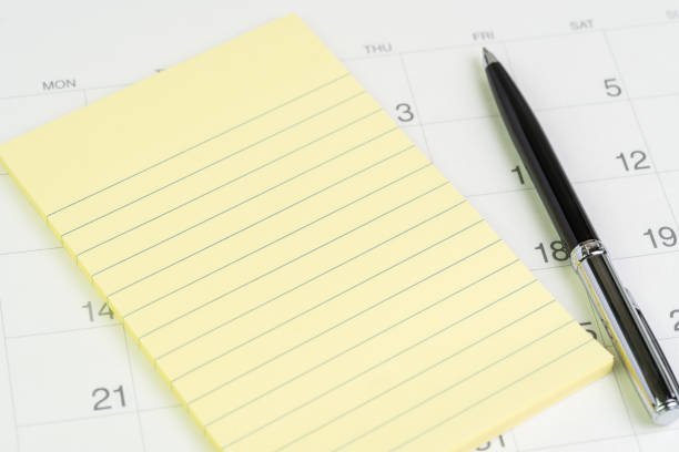 istock Yellow notepad with pen on white clean calendar with date number using as important appointment, event, reservation and business planning concept 1166018139
