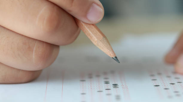 istock Education test in university or high school concept : Hands student holding pencil for testing exams on answer sheet, taking fill in exam document paper at campus classroom. Knowledge learning concept 1166019287