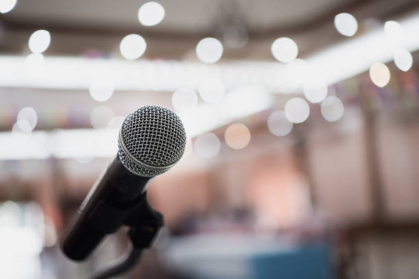 istock Front Microphone on abstract conference hall prepare for speaker on stage in seminar room, Business meeting and education in teaching classroom or Event light convention hall Background. 1166019343
