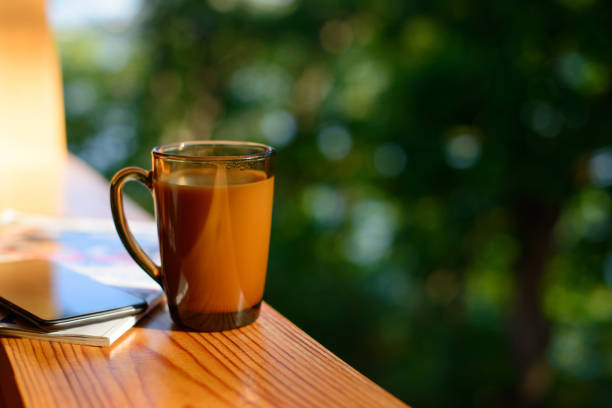 istock Cup of coffee and cellphone on the windowsill over blurred forest background at sunny summer day. Free copy space. 1166020110