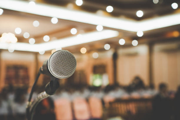 istock Microphone on abstract blurred conference hall prepare for speaker on stage in seminar room. lecture to audience university with bokeh background. Business meeting or education teaching image 1166020251