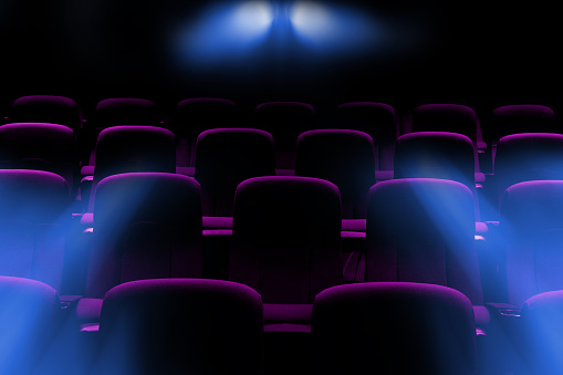 empty movie theater with purple seats with flare light rays from projector