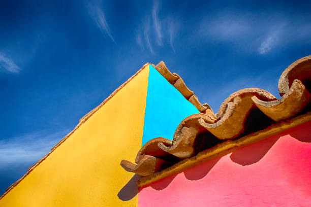 Spanish styled architecture with tiled roof and colorful outside paint Vividly colored walls and spanish tiled roof set this house apart. The day is bright and beautiful and the sky is blue.  Copy space at the top and left of the image. The image is from Mexico. roof tile photos stock pictures, royalty-free photos & images
