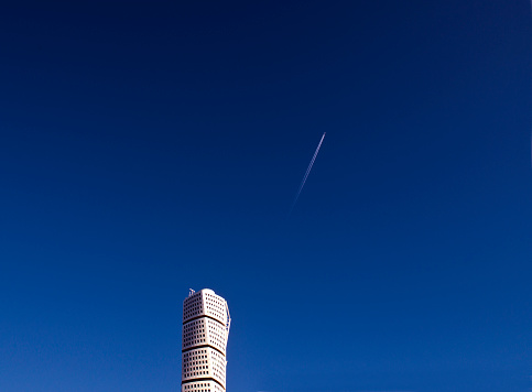 Malmö, Sweden - January 25, 2015. Looking up at Turning Torso and a high flying airplane in the Western Harbor.