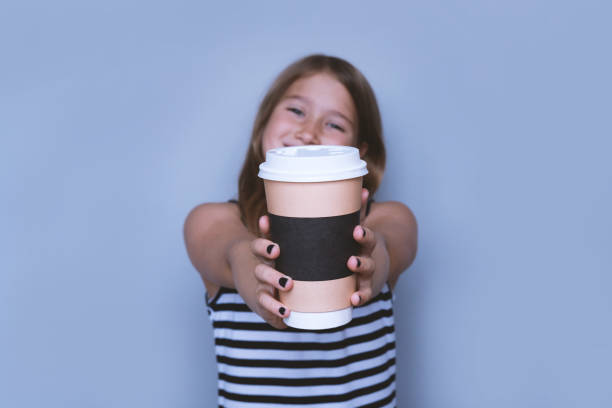 Smiling girl giving, showing coffeecup closeup side view