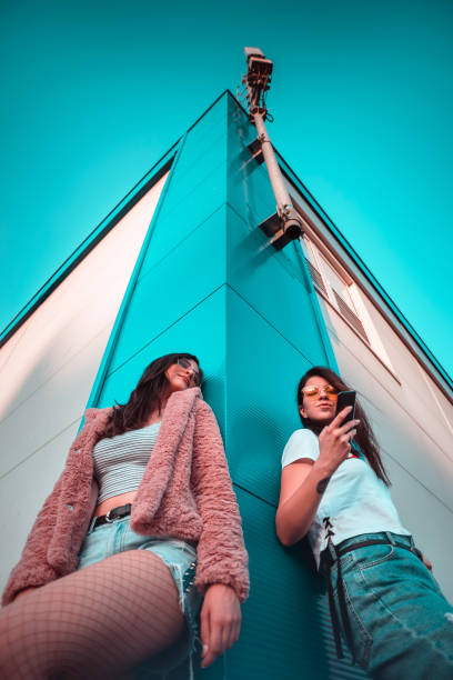 Two young female friends using mobile phone low angle shot