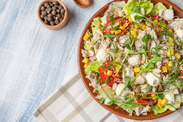 istock Top view green salad with microgreen, corn, chicken and cheese. Salad bowl with copy space. Blue background. Healthy food concpet. Healthy balanced appetizer plate 1166033151