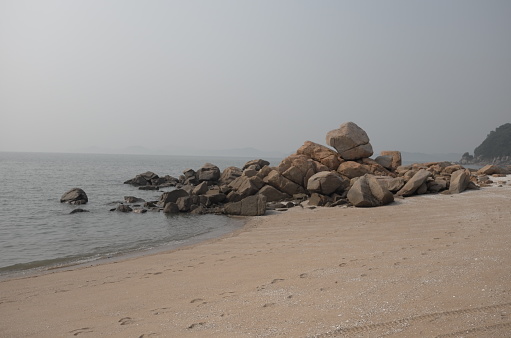 A picture of slightly hazy summer day at high tide. Rocks on a beach