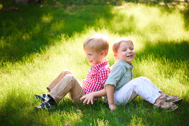 istock Two brothers are sitting on sunny glade in park 1166036761
