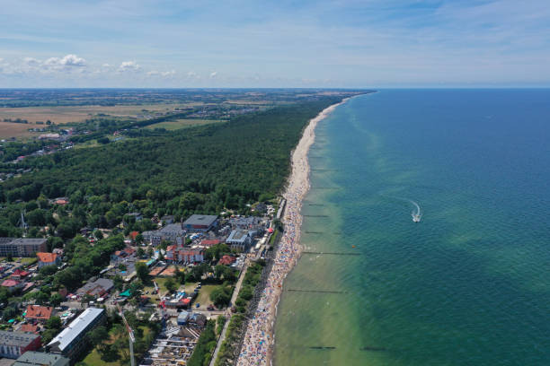 istock Drone aerial perspective view on sunny beach with sunbathers with windbreaks and towels at sea in touristic city. 1166038258