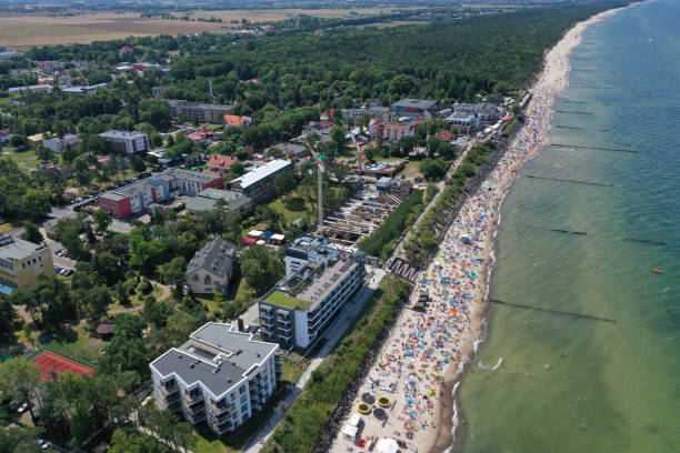 istock Drone aerial perspective view on sunny beach with sunbathers with windbreaks and towels at sea in touristic city 1166038286
