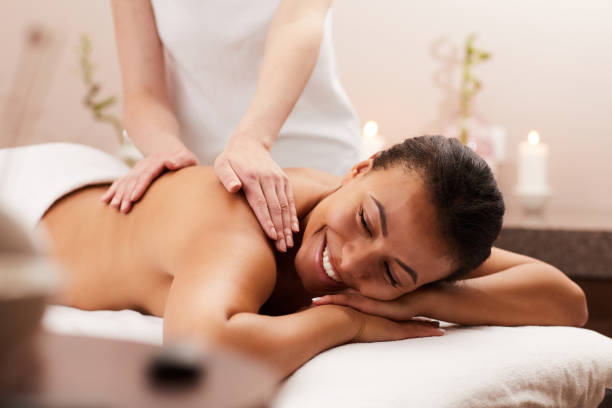 Smiling Woman Enjoying Massage in Spa Portrait of beautiful woman smiling happily while enjoying massage in luxury spa, copy space massaging stock pictures, royalty-free photos & images