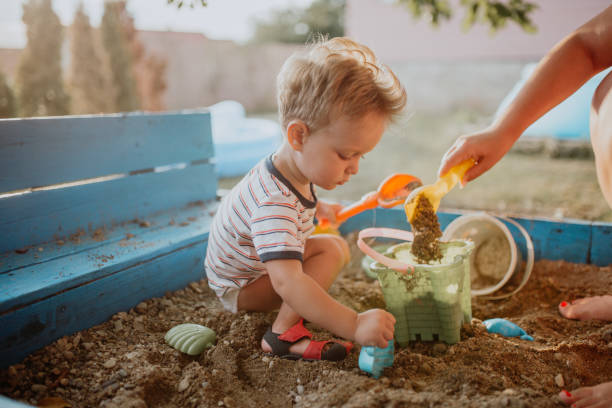 Child plays with his single mother in the sandbox Child plays with mother and enjoys his childhood sandbox photos stock pictures, royalty-free photos & images