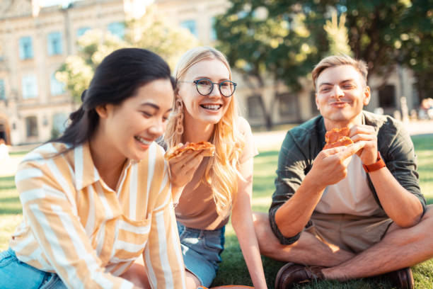 istock Smiling groupmates eating pizza on their picnic. 1166042886
