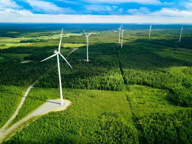 Photo of Aerial view of windmills in summer forest in Finland. Wind turbines for electric power with clean and Renewable Energy