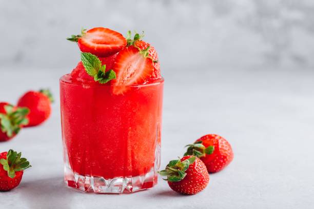 Fresh strawberry rhubarb and watermelon granita with mint on gray stone background
