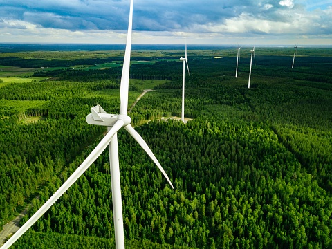 Aerial view of windmills in summer forest in Finland. Wind turbines for electric power with clean and Renewable Energy