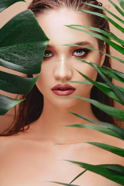 istock young attractive woman posing with a fresh green leaf 1166044249