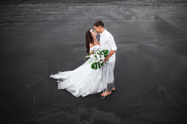 istock Elegant gorgeous bride and groom walking on ocean beach during sunset time. 1166044250