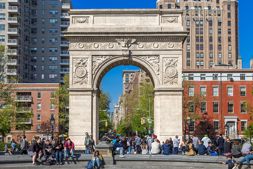 Washington Square Arch as seen from the Washington Square Park on a beautiful spring day. The Arch was built in 1889, to celebrate the one hundredth anniversary of George Washington's inauguration as president of the United States. Tourists walking around are in the image,