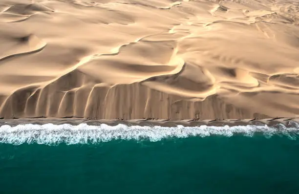 Aerial view of Skeleton coast sand dunes meeting the waves of Atlanic ocean. Skeleton coast, Namibia.