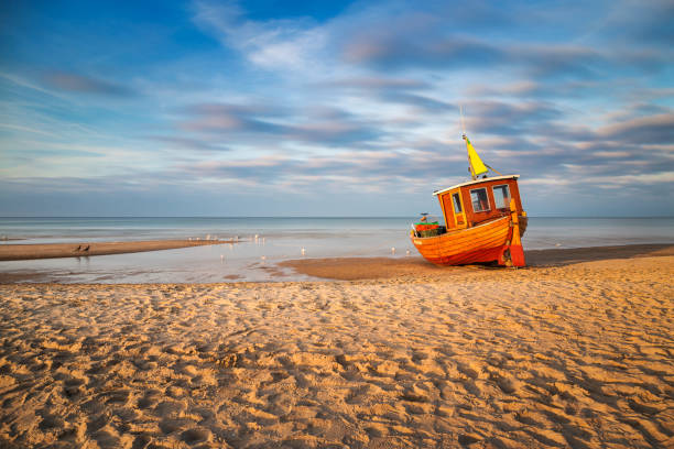 Old fishing boat on Usedom An old, but still used fishing boat at the beach of the village Ahlbeck on the Island Usedom at sunset on a cold day in spring. baltic sea photos stock pictures, royalty-free photos & images