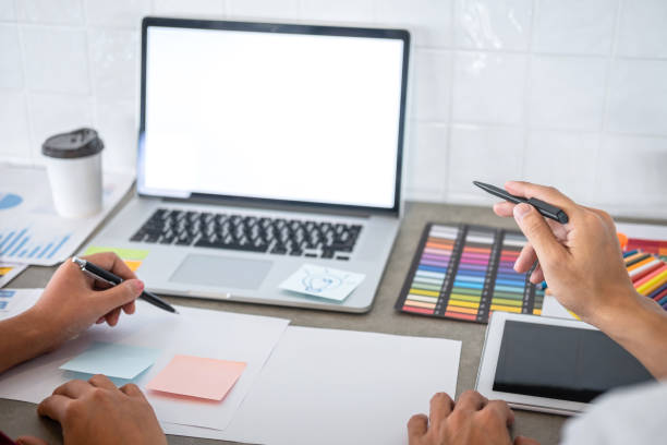 istock Teamwork of young creative designers working on project together and choose color swatch samples for selection coloring on digital graphic tablet and equipment at workplace 1166053242