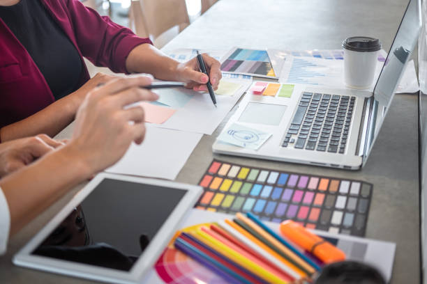 istock Teamwork of young creative designers working on project together and choose color swatch samples for selection coloring on digital graphic tablet and equipment at workplace 1166053793