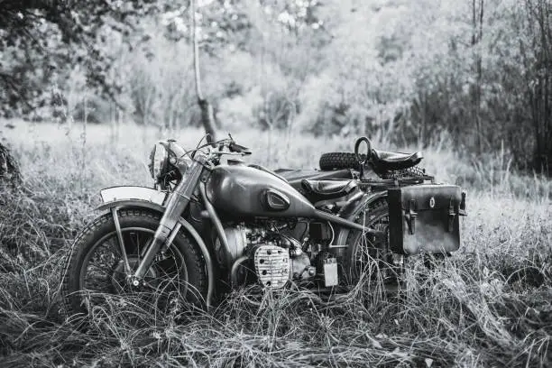 Photo of Old Tricar, Three-Wheeled Motorbike Of Wehrmacht, Armed Forces Of Germany Of World War II Time In Summer Forest. Photo In Black And White Colors