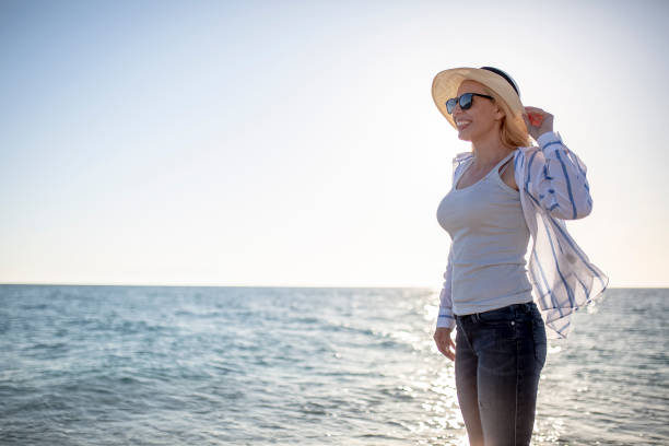 istock Woman watching sunset by the sea 1166056229