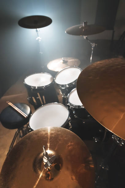 istock Modern drum set prepared for playing in a dark rehearsal room on stage with a bright spotlight. 1166071846