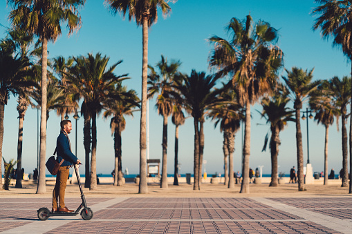 Man riding an electric scooter in Valencia alongside ‘’Platja del cabanyal’’