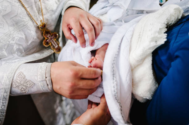 The sacrament of baptism. Newborn baby during christening and chrismation. Infant baby baptism in Holy water. The sacrament of baptism. Newborn baby during christening and chrismation. Infant baby baptism in Holy water. godfather godparent stock pictures, royalty-free photos & images